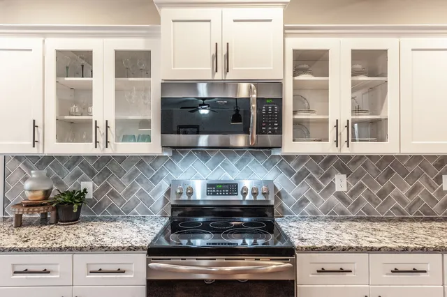 a kitchen with stainless steel appliances granite countertop white cabinets and a stove top oven