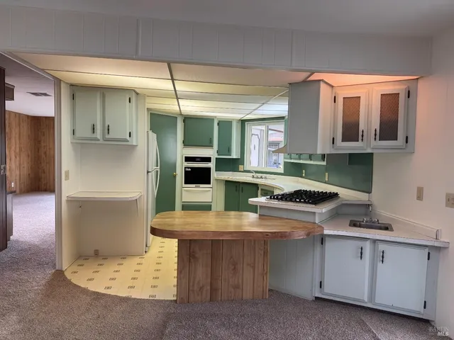a kitchen with kitchen island granite countertop a sink cabinets and stainless steel appliances