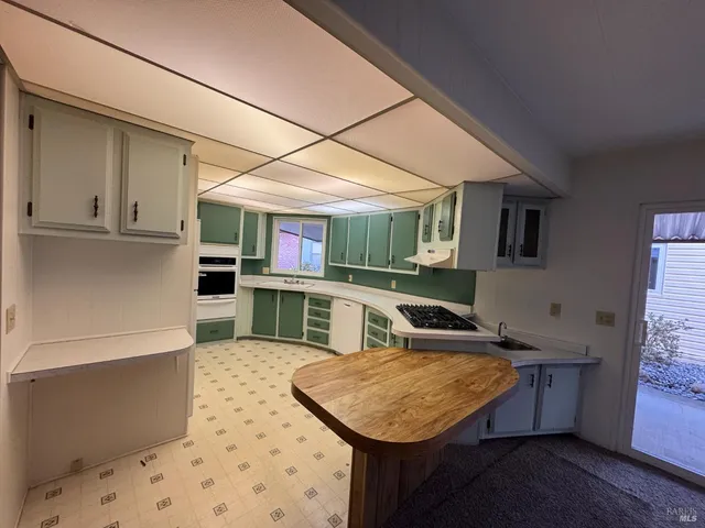 a kitchen with stainless steel appliances kitchen island granite countertop a table chairs sink and cabinets