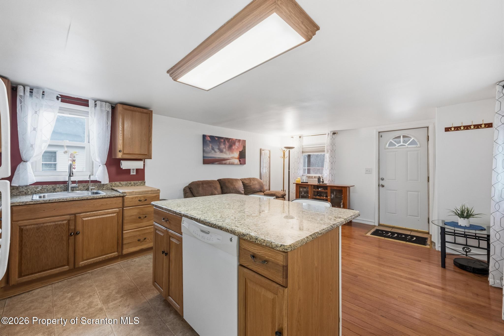 138 Swetland Street Duryea, PA 18642 - Photo 7 of 34 a hall with kitchen island a stove a sink dishwasher and a refrigerator with wooden floor