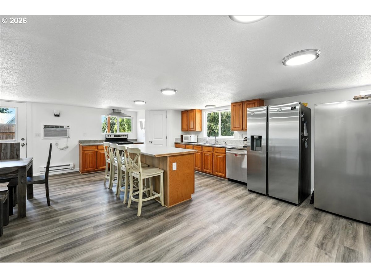 34155 Southeast Moss Hill Road Estacada, OR 97023 - Photo 19 of 26 a kitchen with stainless steel appliances kitchen island granite countertop a table chairs and a refrigerator