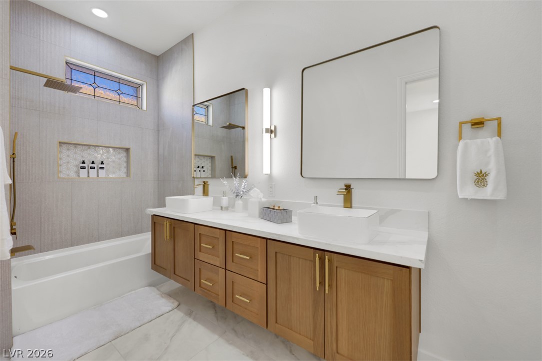 5015 Rivedro Street Las Vegas, NV 89135 - Photo 18 of 91 A well-appointed primary bathroom showcases dual vessel sinks atop a floating wood vanity, complemented by sleek mirrors and a spacious soaking tub.