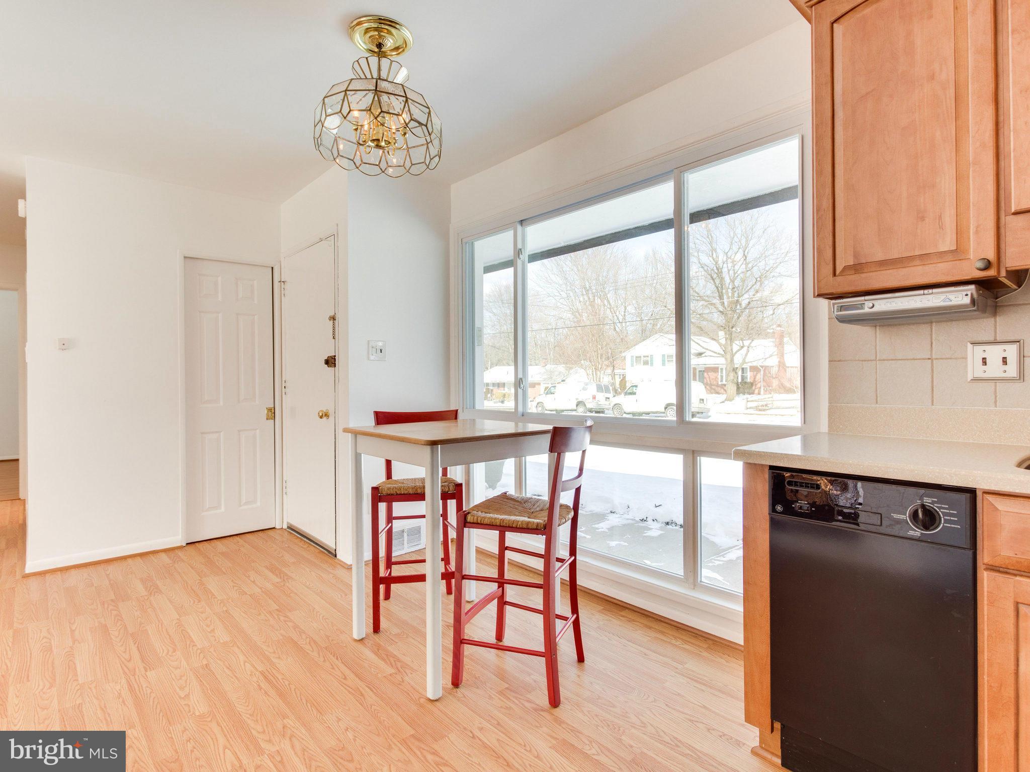 7315 Inzer Street Springfield, VA 22151 - Photo 4 of 23 a dining room with wooden floor a chandelier a glass table and chairs