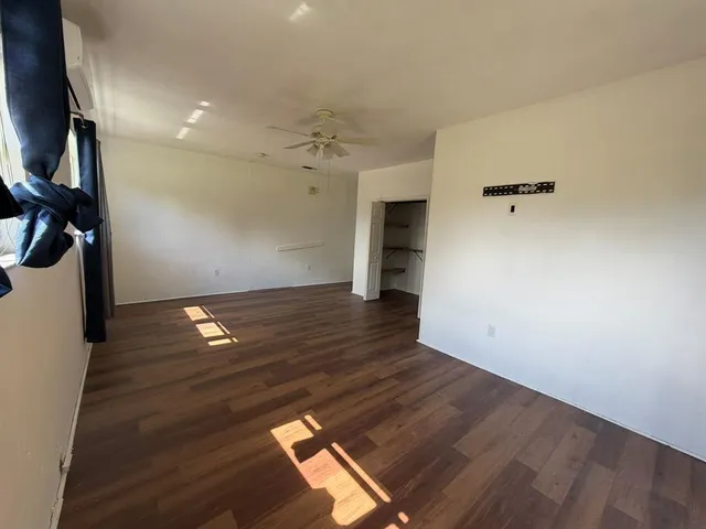 an empty room with wooden floor and windows