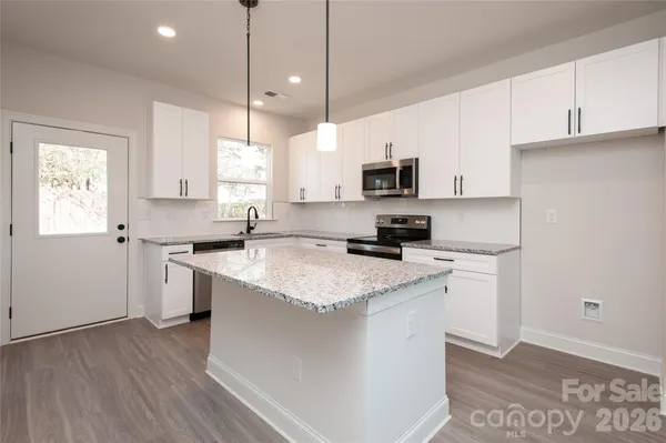 a kitchen with stainless steel appliances granite countertop a sink a stove a microwave a refrigerator a sink and dishwasher with wooden floor