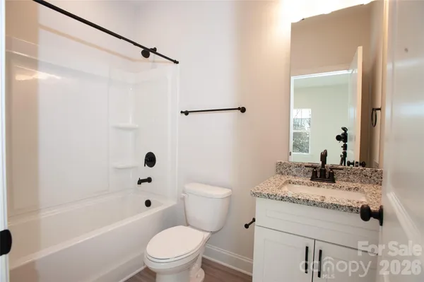 a bathroom with a granite countertop sink a toilet and shower