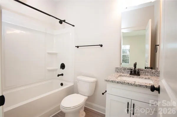 a bathroom with a granite countertop sink a toilet and shower