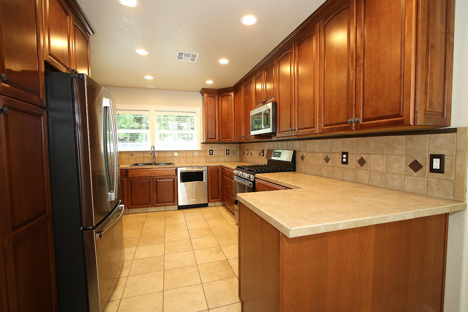 526 Melrose Street Modesto, CA 95354 - Photo 13 of 27 a kitchen with kitchen island granite countertop wooden cabinets stainless steel appliances a sink and a large window