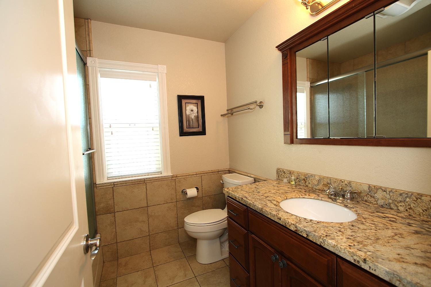526 Melrose Street Modesto, CA 95354 - Photo 21 of 27 a bathroom with a granite countertop sink toilet and mirror