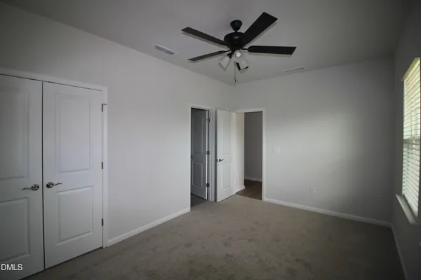 an empty room with a ceiling fan and a window