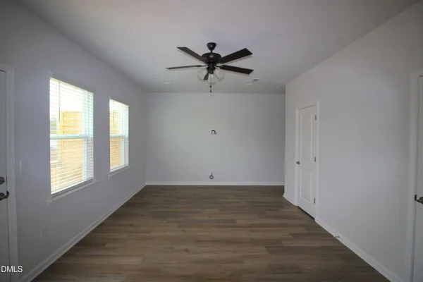 a view of a livingroom with a window a ceiling fan and wooden floor