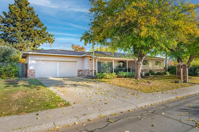 a view of a house with a yard and large tree