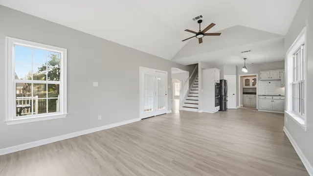 a view of an empty room with a window and wooden floor
