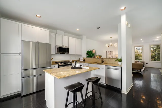 a kitchen with stainless steel appliances a refrigerator a stove a sink a dining table and chairs