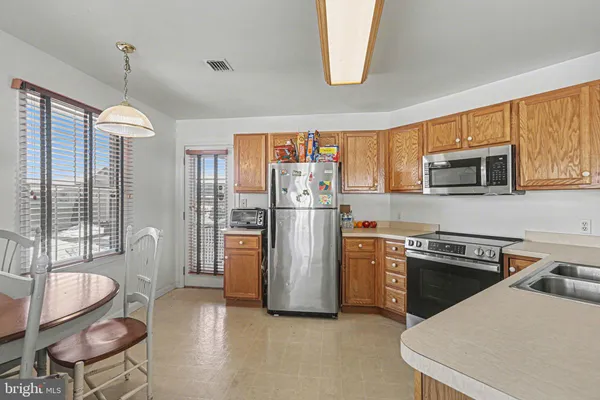 a kitchen with stainless steel appliances granite countertop a refrigerator a stove a sink dishwasher a dining table and chairs with wooden floor