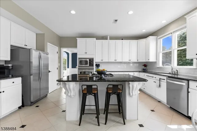 a kitchen with stainless steel appliances a table chairs sink refrigerator and cabinets