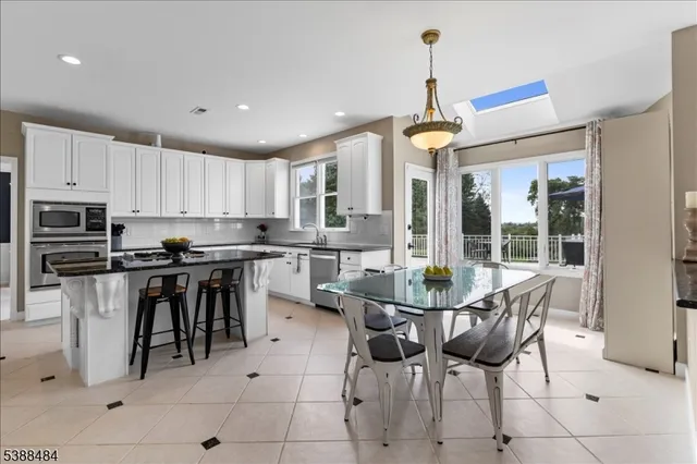 a dining room with stainless steel appliances kitchen island granite countertop a table and chairs