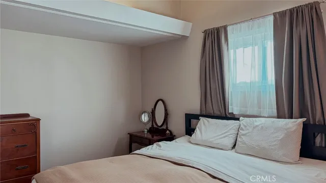 a bedroom with a bed lamp and a large window