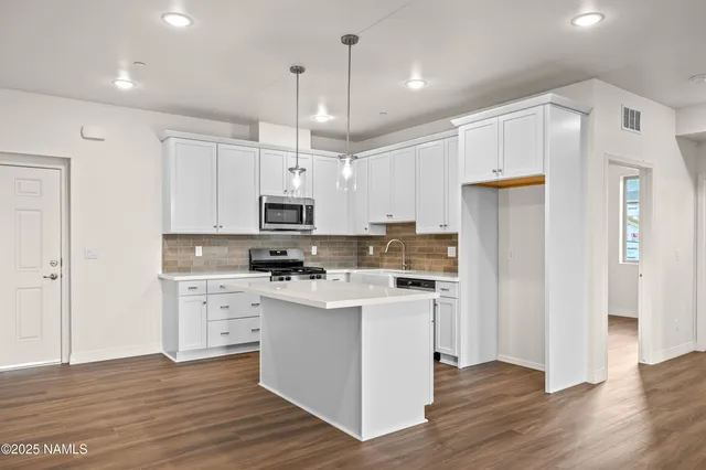 a kitchen with stainless steel appliances cabinets a sink and wooden floor