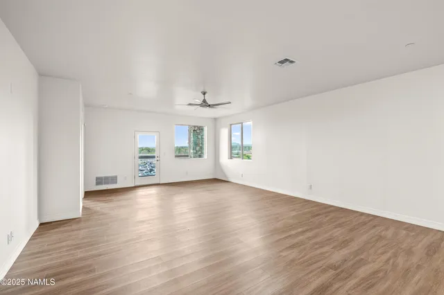 an empty room with wooden floor and windows