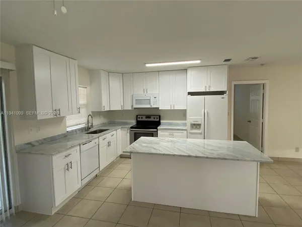 a kitchen with granite countertop a refrigerator and a sink