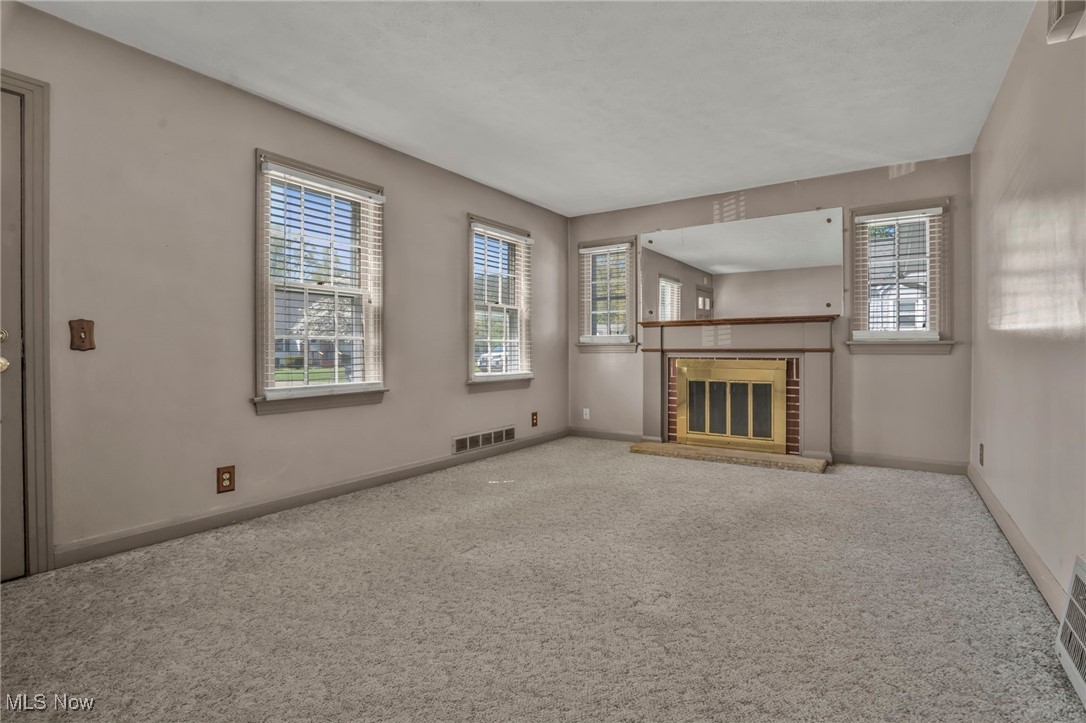 4529 15th Street Northwest Canton, OH 44708 - Photo 4 of 21 Unfurnished living room featuring carpet floors, plenty of natural light, and a fireplace