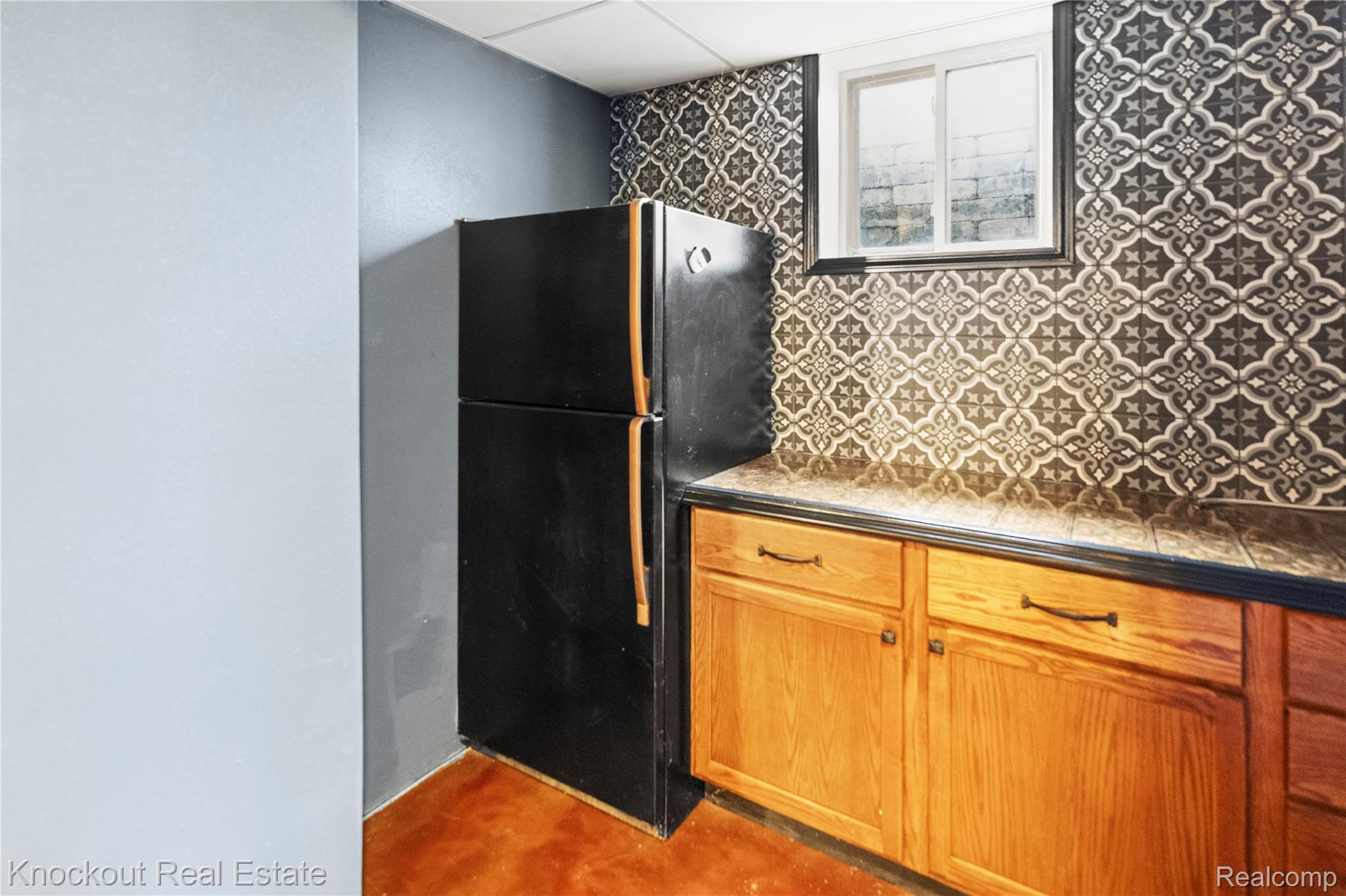 5750 Maple Road Frankenmuth, MI 48734 - Photo 41 of 60 Full-height patterned tile backsplash, wood-finish cabinetry, and a black appliance
