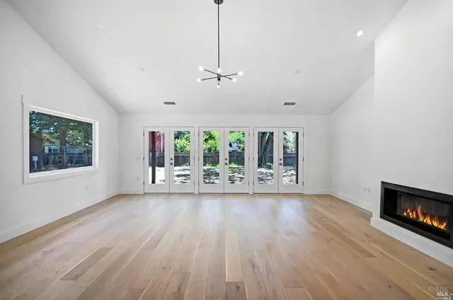 a view of an empty room with wooden floor fireplace and a window
