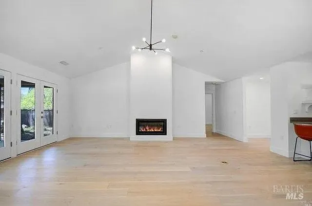 a view of an empty room with window and wooden floor
