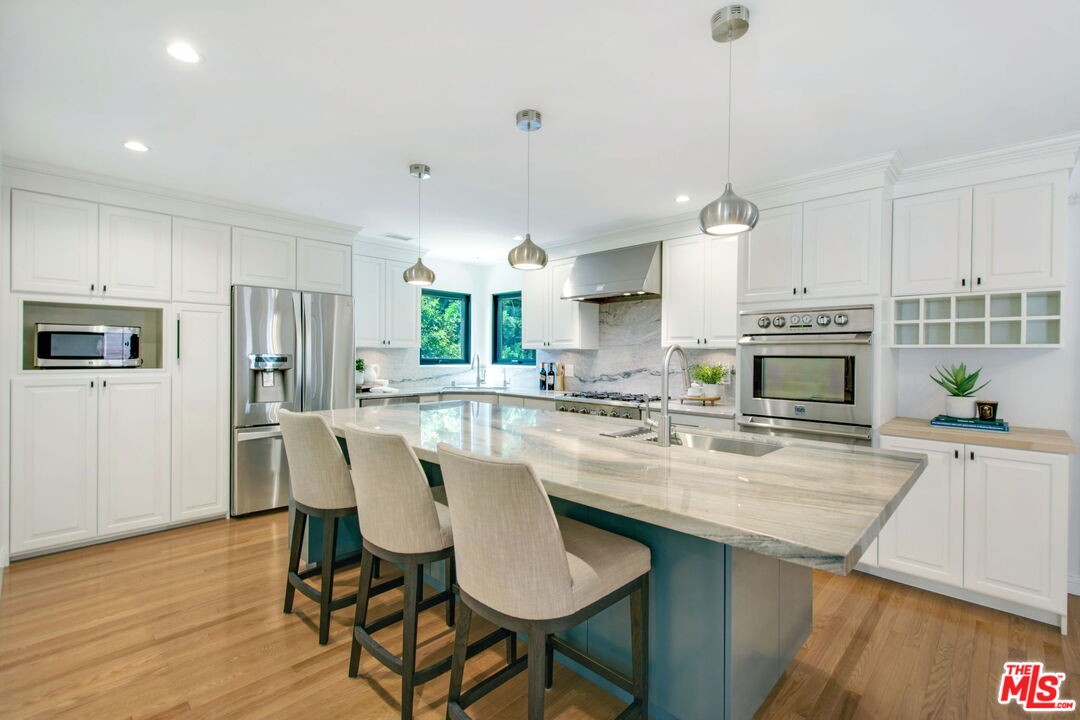 3558 Muirfield Road South Los Angeles, CA 90016 - Photo 4 of 23 a kitchen with stainless steel appliances granite countertop a stove a sink a refrigerator a kitchen island with a dining table and chairs