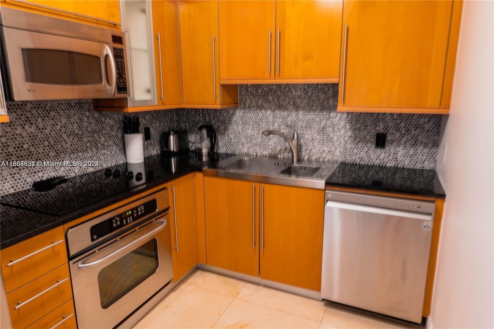 6365 Collins Avenue, Unit 2710 Miami Beach, FL 33141 - Photo 14 of 24 a kitchen with stainless steel appliances granite countertop a stove and a microwave