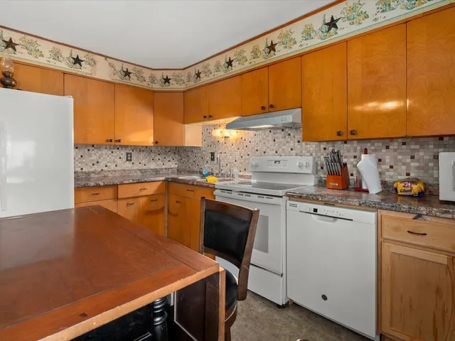 a kitchen with a stove a sink a kitchen island with chairs and wooden cabinets