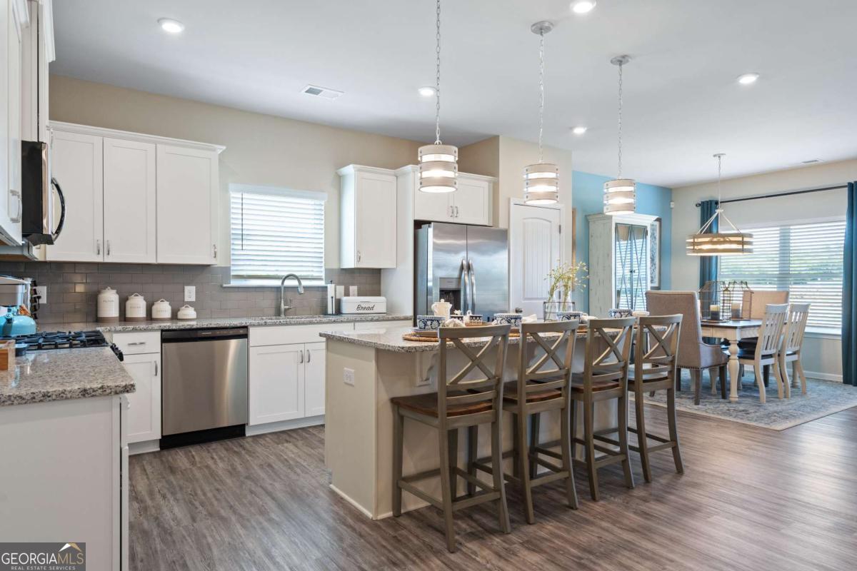 157 Creekside Road, Unit (LOT 32) Eatonton, GA 31024 - Photo 9 of 28 a large kitchen with cabinets wooden floor white stainless steel appliances and chairs