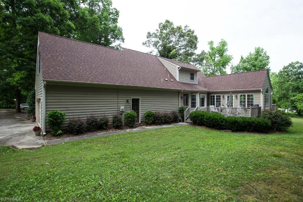 5707 Roundtable Road Greensboro, NC 27407 - Photo 25 of 29 Backyard looking at garage and right side deck. Paved driveway next to house. Side door of garage exits onto sidewalk-- just a few steps from the kitchen door.
