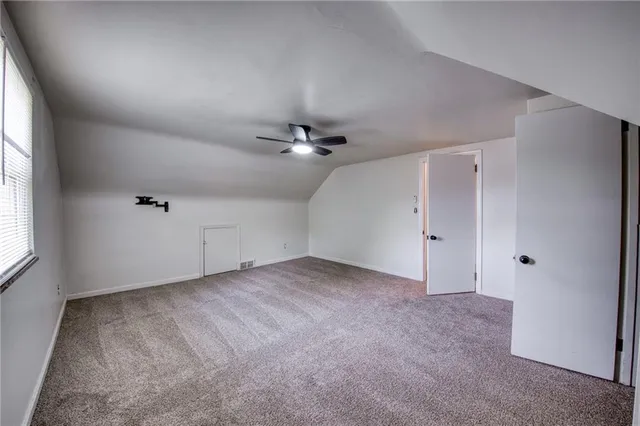 an empty room with chandelier fan and windows