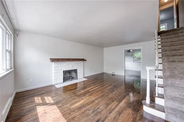 a view of empty room with wooden floor and fireplace