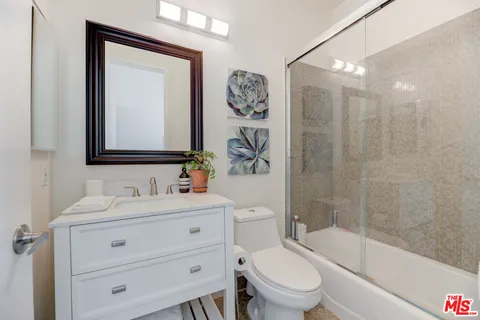 a bathroom with a toilet a sink a mirror a bathtub and vanity