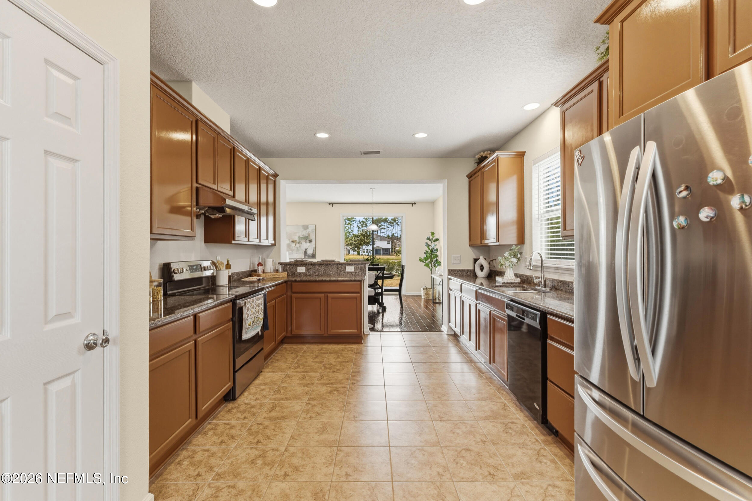 270 Carnation Street St. Johns, FL 32259 - Photo 12 of 56 a large kitchen with stainless steel appliances granite countertop a stove top oven a sink dishwasher a refrigerator and white cabinets with wooden floor