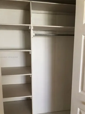 a view of walk in closet with empty racks