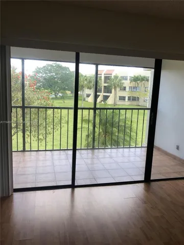 an empty room with sliding glass door and wooden floor