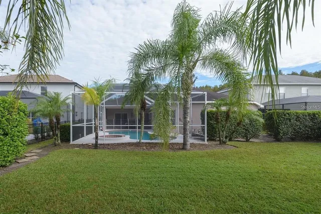 a view of a house with a yard and palm trees