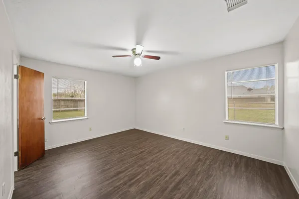 a view of an empty room with a window and wooden floor