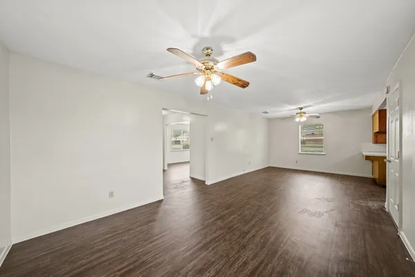 a view of an empty room with window and wooden floor