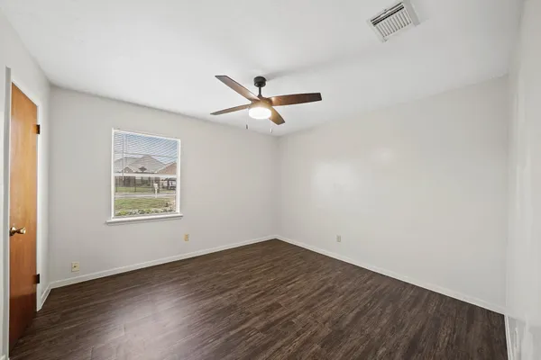 an empty room with wooden floor and ceiling fan
