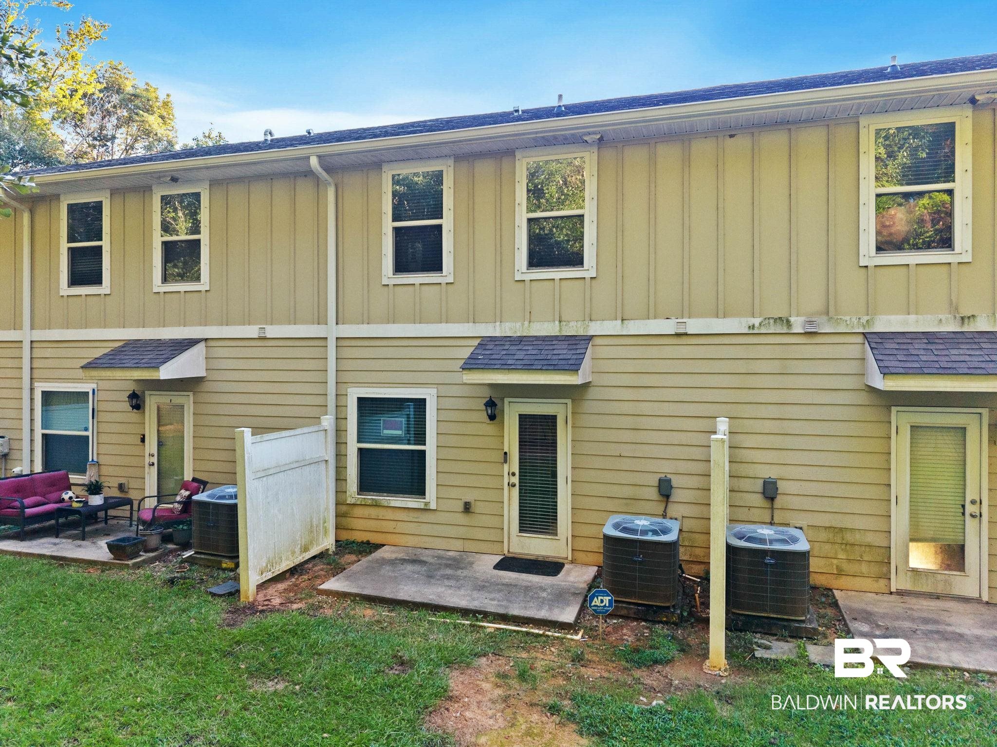 25806 Pollard Road, Unit 24 Daphne, AL 36526 - Photo 25 of 33 Rear view of property with a patio, board and batten siding, a shingled roof, and a lawn