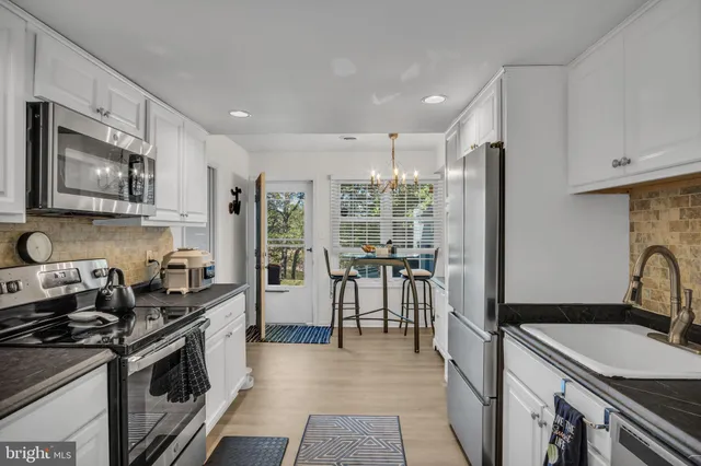 a kitchen with granite countertop a stove top oven sink and stainless steel appliances
