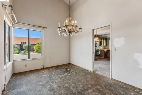 en empty room with windows and chandelier