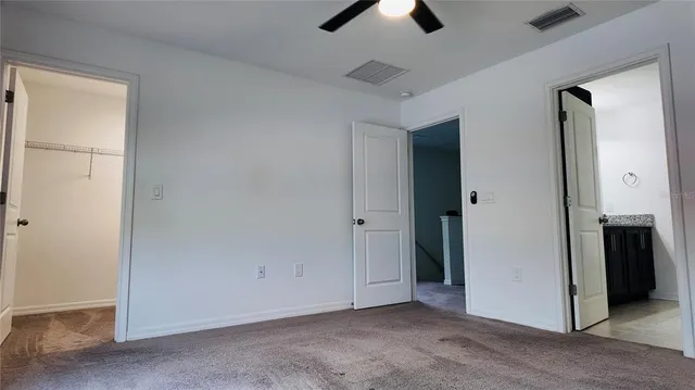 an empty room with closet and a ceiling fan