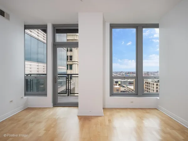 an empty room with windows and view of kitchen