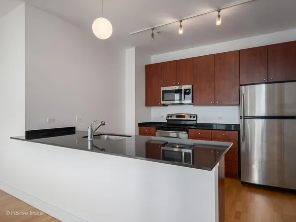 a kitchen with granite countertop a refrigerator stove and microwave